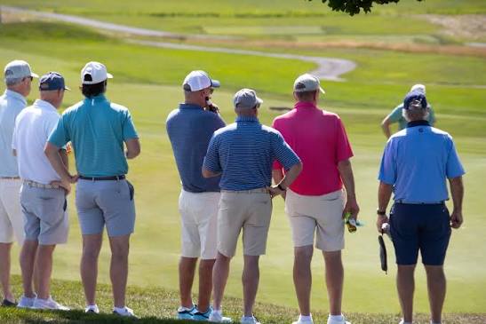 A group of golfers watching a shot at a charity outing